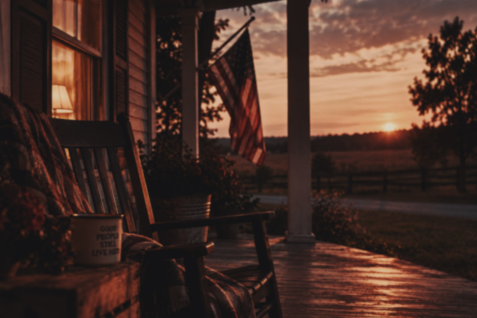A warmly lit front porch overlooking the countryside at sunset.